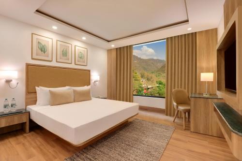 a bedroom with a bed and a large window at Lemon Tree Hotel, Tapovan Rishikesh in Rishīkesh