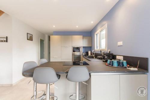 une cuisine avec un grand îlot et des tabourets de bar dans l'établissement La Suretière, à Montmartin-sur-Mer