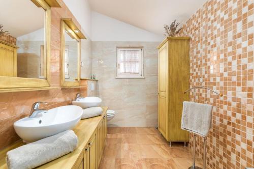 un bagno con due lavandini, uno specchio e un water di Villa Klara a Kaštelir (Castellier)