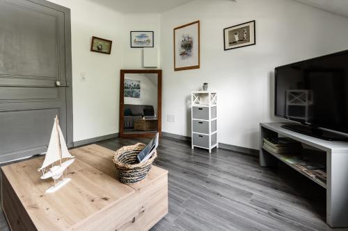ein Wohnzimmer mit einem TV und einem Couchtisch aus Holz in der Unterkunft Villa de la plage in Saint-Brevin-les-Pins