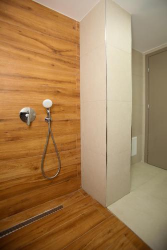 a shower in a room with a wooden wall at Belvedere Hotel & SPA in Vlorë