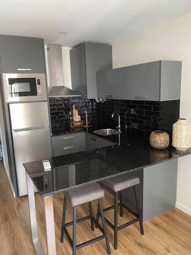 a kitchen with a black counter top and a refrigerator at Apartamento Porta14 2 in Chaves