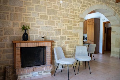 a living room with a brick fireplace and chairs at Aloe & Lotus Villas in Prinés
