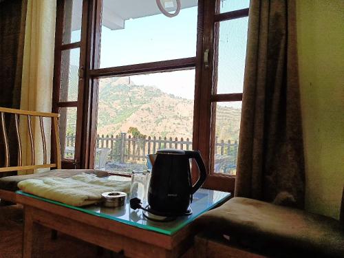a tea kettle sitting on a table in front of a window at The Tranquil hotel in Chakrāta