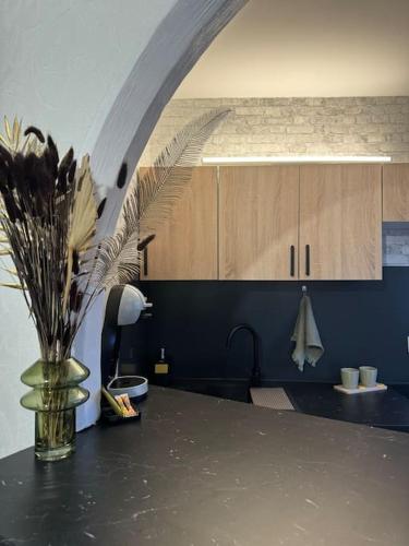 une cuisine avec une table avec un vase de fleurs dans l'établissement Le Bouchon - Appartement Cosy - Wifi, à Talence