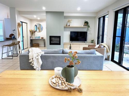 a living room with a blue couch and a table at Anchor Ocean Grove - Fireplace, Wineries, Cafes, Bars, Surf in Ocean Grove