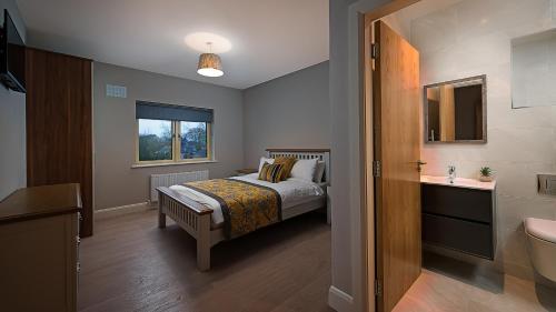 een slaapkamer met een bed en een badkamer met een wastafel bij Kilmurry Lodge Hotel in Limerick