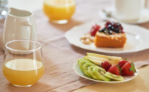 a table with plates of fruit and a glass of orange juice at Pamperduto Country Resort in Porto Potenza Picena