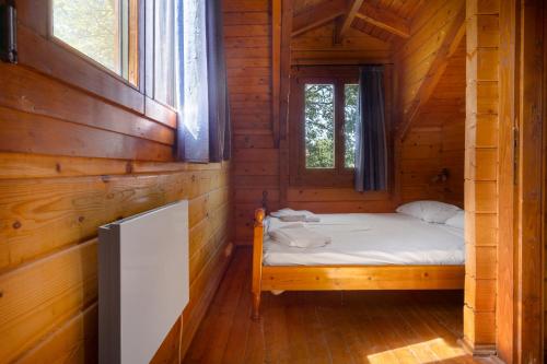 a small bedroom with a bed in a wooden cabin at Zeus-Village οικισμός φινλανδικών chalet με πισίνες & γυμναστήριο in Mólos
