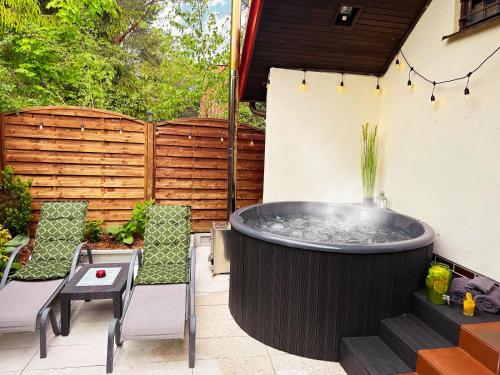 a hot tub in a backyard with chairs and a table at Domek Kamień in JeleÅ„ska Huta