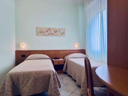アルビソーラ・スペリオーレにあるHotel San Giorgioのベッド2台とテーブルが備わるホテルルームです。