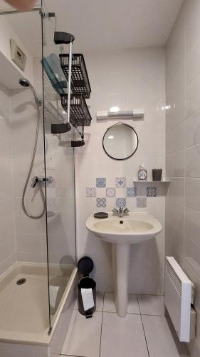 een witte badkamer met een wastafel en een douche bij La Baule, studio cosy. Quartier Jumping/Atlantia in La Baule