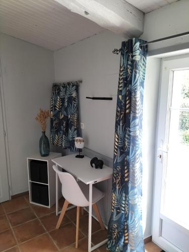 une table et des chaises dans une pièce avec des rideaux dans l'établissement PETITE MAISON 2 PIECES POUR 4 à 5 personnes, à Le Boupère