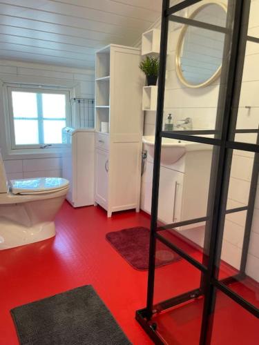 a bathroom with a white toilet and a red floor at Sentrumsnært studio ved Bugården in Sandefjord