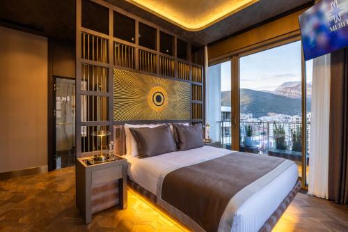 a bedroom with a large bed and a large window at Merit Starlit Hotel & Residences in Budva