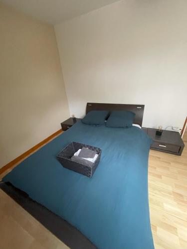un lit bleu avec une boîte dessus dans l'établissement Location chambre au calme proche circuit des 24 heures, à Mulsanne