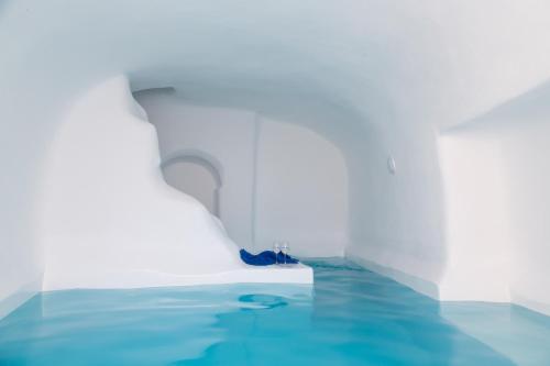 a white room with blue water in it at Trieris Villa & Suites in Fira