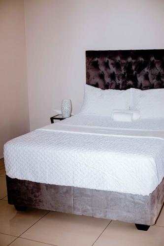 a bedroom with a large bed with white sheets at Guest House Auasblick by State House in Windhoek