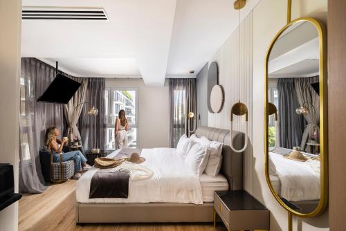 a woman sitting on a bed in a bedroom with a mirror at Allenbeach TLV- apart Hotel- Adults only in Tel Aviv