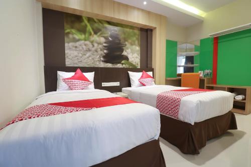 two beds in a room with a green wall at Super OYO Balitone Residence in Denpasar