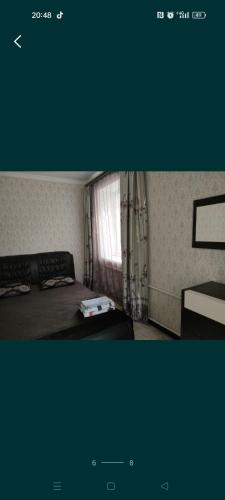 Habitación pequeña con cama y ventana en Уютная двухкомнатная квартира в Актобе, en Aktobe