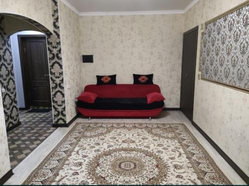 a red couch in a room with a rug at Уютная двухкомнатная квартира в Актобе in Aktobe