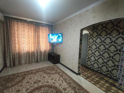 sala de estar con TV y ventana grande en Уютная двухкомнатная квартира в Актобе, en Aktobe
