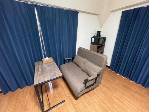 a chair and a table in a room with blue curtains at パルム天神西 in Susakiuramachi