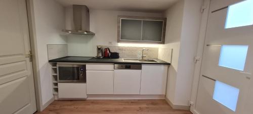 une cuisine avec des armoires blanches et un évier dans l'établissement Appartement avec jardin, à Saint-Malo