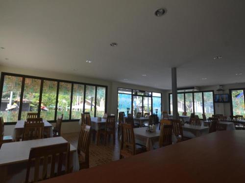 un comedor con mesas, sillas y ventanas en The Green Hotel, en Ko Lipe