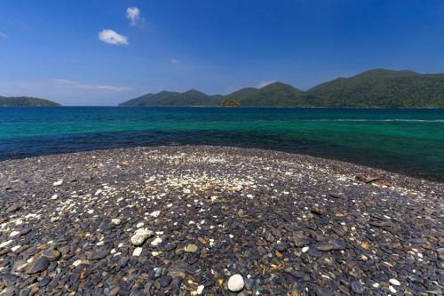 a rocky beach with water and mountains in the background at The Green Hotel in Ko Lipe