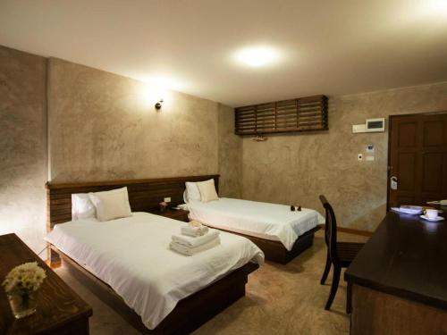 een hotelkamer met 2 bedden en een bureau bij At home boutique in Ban Long