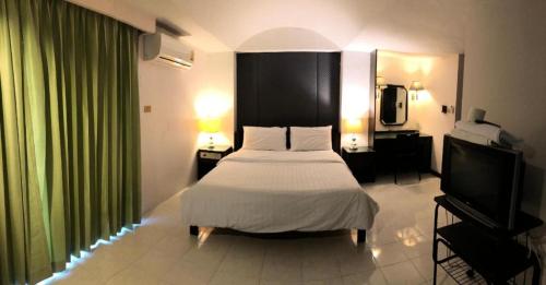 a bedroom with a bed and a flat screen tv at S.C. Heritage Hotel in Hat Yai