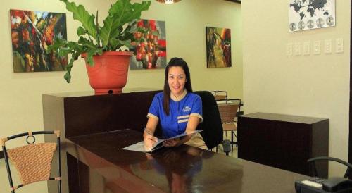 une femme assise à une table avec un livre dans l'établissement Filigans Hotel, à Puerto Princesa