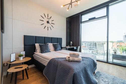 a bedroom with a large bed and a clock on the wall at Q18 ApartHotel in Bydgoszcz