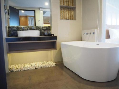 ein Badezimmer mit einer großen weißen Badewanne und einem Waschbecken in der Unterkunft The Vista Hotel By Satit Group in Ban Khlong Phruan