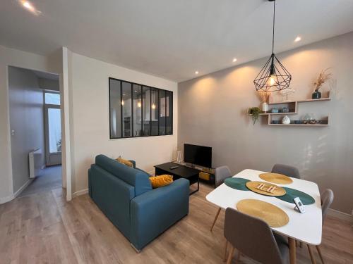 un salon avec une table et un canapé bleu dans l'établissement Maison 2 chambres avec cour privée, à 200m de la plage et proche commerces - Les Sables-d'Olonne - FR-1-197-557, à Les Sables-dʼOlonne