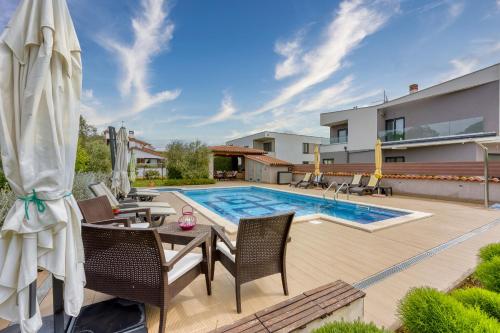 - une piscine dans un jardin avec une table et des chaises dans l'établissement Apartments Brioni Colors, à Pula