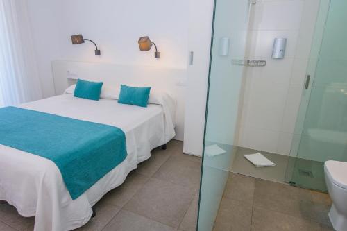 a bedroom with a bed and a glass shower at Hostal La Isla in Carboneras