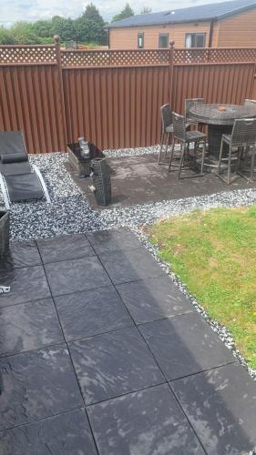 a patio with a table and chairs next to a fence at Kingfisher Lodge Long Acre Holiday Park in Evesham
