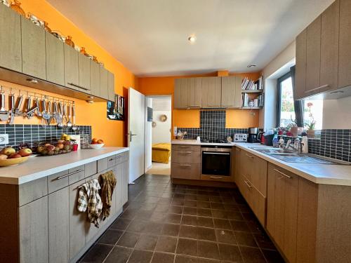 une grande cuisine avec des murs orange et des placards en bois dans l'établissement villa pres des dunes, à La Couarde-sur-Mer