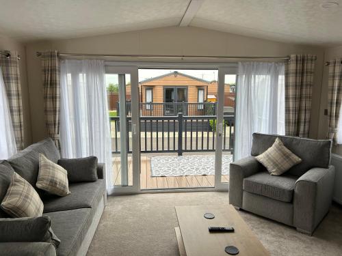 a living room with a couch and an open door at Kingfisher Lodge Long Acre Holiday Park in Evesham
