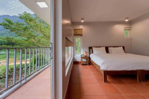 a bedroom with a bed and a balcony at Chay Lap Farmstay Phong Nha in Ðá Lòn