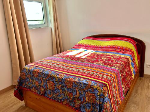 a bed with a colorful blanket on it in a room at Red Rose of Summer Flat with private garden - Wilena Holiday Home in Chens-sur-Léman
