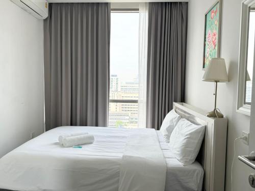 Cama blanca en habitación de hotel con ventana en The Rich Sukhumvit 3 by Nana Best, en Bangkok