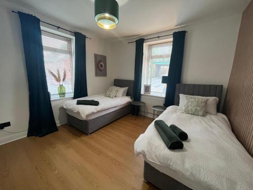 a bedroom with two beds and two windows at Modern & retro two bedroom apartment in Barnsley in Barnsley