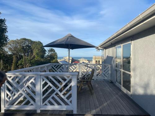 a patio with an umbrella and chairs on a deck at Little Sweetie in Oamaru