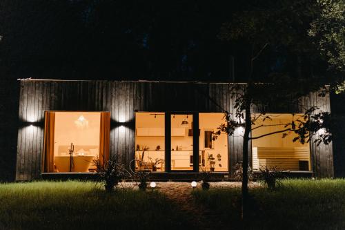 a building with large glass windows at night at Ezernams SPA in Kaukuri