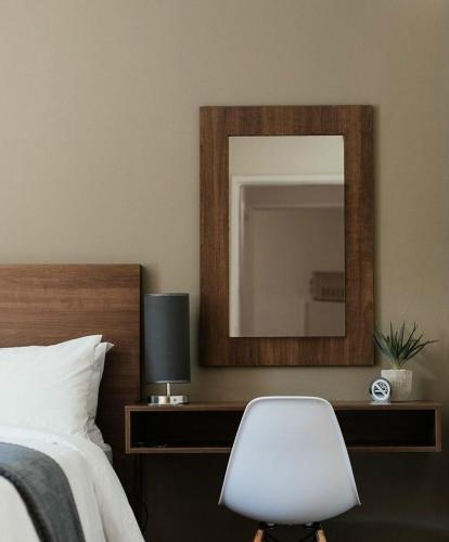 a bedroom with a mirror and a white chair at 27 on Gunn Street in Bloemfontein