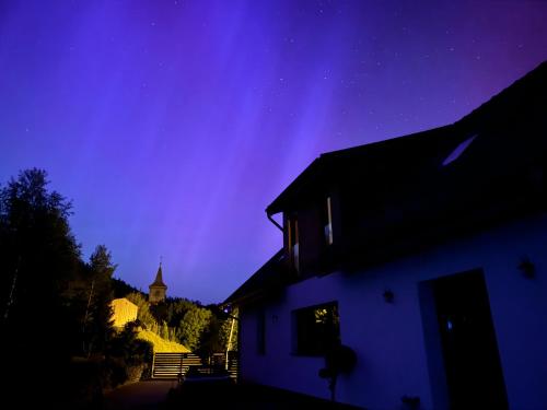 a night view of a house with the aurora in the sky at Przygórze - dom w Górach Sowich in Przygórze